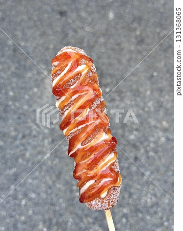 Korean corn dog, a crispy snack coated in a sweet batter, often stuffed with sausage, cheese, or both. Topped with sugar, ketchup, or mustard for a delightful mix of flavors and textures. 131368065