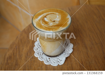 A beautifully crafted latte, featuring creamy foam art on top of rich espresso. Perfect for coffee related projects, this image captures the warmth and inviting nature of a classic cafe experience. 131368159