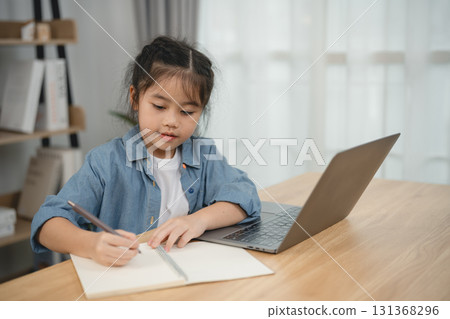 Young Girl Engaged in Creative Writing Activity at Home with Laptop and Notebook in Cozy Workspace Filled with Natural Light and Soft Decor Young Girl Engaged in Creative Writing Activity at Home with Laptop and Notebook in Cozy Workspace Filled with Natural Light and Soft Decor 131368296