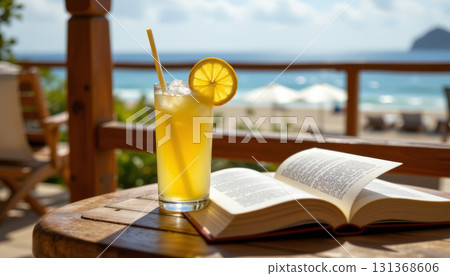 Refreshing lemonade with lemon slice and straw on wooden table next to open book by beach under sunny sky 131368606
