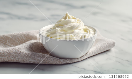 Whipped cream in white bowl on beige cloth with marble background, soft texture and creamy appearance for dessert topping or ingredient 131368952