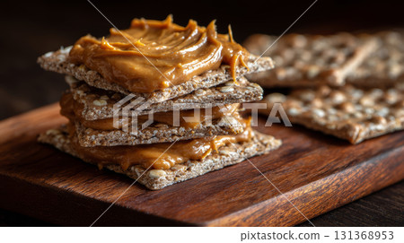 Crunchy crispbread stacked with creamy peanut butter spread on wooden board, showcasing healthy and delicious snack option 131368953