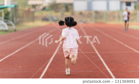 Excited Child With Pigtails Running On Track During Outdoor Sports Practice In Bright Sunshine On Summer Day At School Playground Excited Child With Pigtails Running On Track During Outdoor Sports Practice In Bright Sunshine On Summer Day At School Playground 131369091