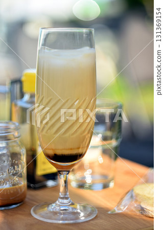 Iced coffee latte served in elegant glass on wooden table Iced coffee latte served in elegant glass on wooden table 131369154
