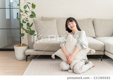 Smiling young Asian woman relaxing in the living room at home 131369383