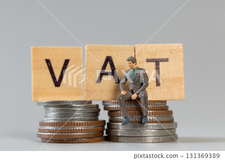 VAT Tax Concept with Miniature Businessman on Coin Stacks 131369389