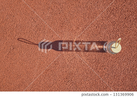 Clear water bottle with wooden cap casting long shadow on red textured surface 131369906