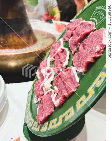 aw, fresh, high-quality red meat sits on a Chinese plate, standing upright on the table. Slices of raw meat before cooking. 131369966
