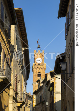 Pienza clock tower dominating Tuscan old town street 131370373
