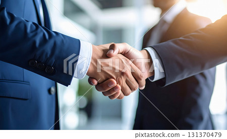Businessmen handshake under bright light symbolizing trust and success 131370479