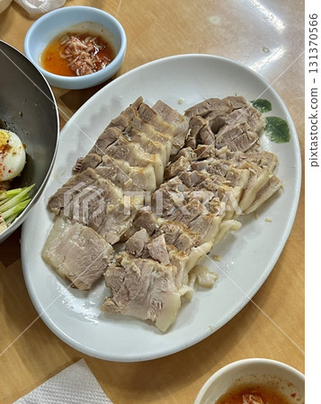 Suyuk, a traditional Korean dish of boiled pork slices, tender and juicy, often served with salted shrimp sauce, garlic, and ssamjang. Perfect for wrapping in lettuce for a flavorful, balanced bite. Suyuk, a traditional Korean dish of boiled pork slices, tender and juicy, often served with salted shrimp sauce, garlic, and ssamjang. Perfect for wrapping in lettuce for a flavorful, balanced bite. 131370566