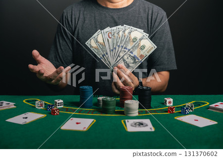Asian man dealer or croupier shuffles poker cards betting in casino holding mobile phone and dollars happy exciting smile cheerful on black background, Dealer man invitation bet playing cards. 131370602