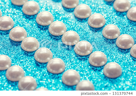 Diagonal rows of pearl hemisphere beads on a blue glitter background Diagonal rows of pearl hemisphere beads on a blue glitter background 131370744