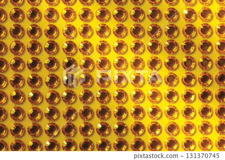 Rows of artificial rhinestones on a yellow background 131370745