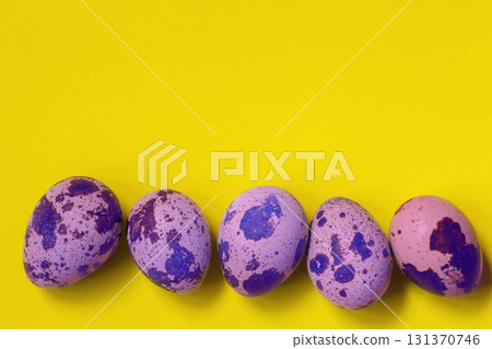 Line of purple colored quail eggs in bottom on yellow background. Easter concept. Line of purple colored quail eggs in bottom on yellow background. Easter concept. 131370746