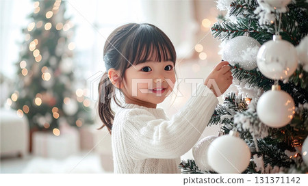 Cute little girl decorating a Christmas tree 131371142