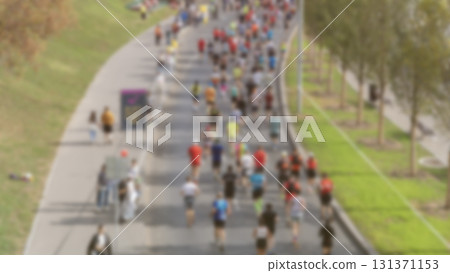 Marathoners sprinting on a city street, a panoramic view, a multitude of runners, a detailed look at the legs of runners participating in a marathon, men jogging on a paved road, athletic events. 131371153