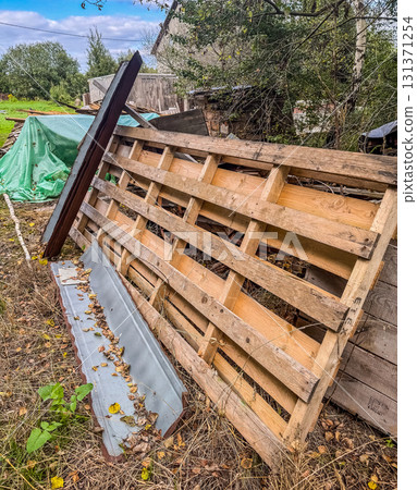 Abandoned wooden pallet leaning against a shed surrounded by grass, metal sheets, and rural garden elements. Recycling, sustainability, rustic lifestyle, and countryside theme. High quality photo Abandoned wooden pallet leaning against a shed surrounded by grass, metal sheets, and rural garden elements. Recycling, sustainability, rustic lifestyle, and countryside theme. High quality photo 131371254