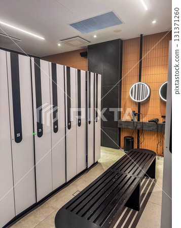 Stylish locker room with numbered lockers, wooden benches, and illuminated mirrors. Ideal for fitness, lifestyle, and interior design themes. High quality photo Stylish locker room with numbered lockers, wooden benches, and illuminated mirrors. Ideal for fitness, lifestyle, and interior design themes. High quality photo 131371260
