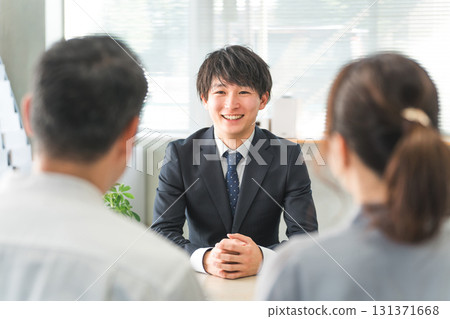 A young Asian businessman and his customer couple serving in a showroom/business negotiation space A young Asian businessman and his customer couple serving in a showroom/business negotiation space 131371668