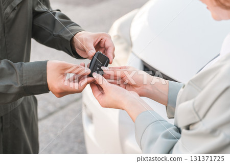A male auto mechanic staff member taking car keys from a female customer A male auto mechanic staff member taking car keys from a female customer 131371725