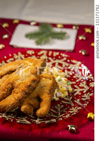 Fried carp with potato salad Christmas dinner on red tablecloth 131371762