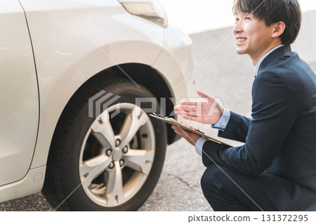 Male salesman/appraiser staff using a checklist to assess and estimate a car Male salesman/appraiser staff using a checklist to assess and estimate a car 131372295