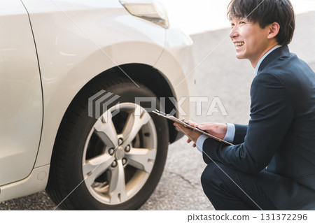 Male salesman/appraiser staff using a checklist to assess and estimate a car 131372296