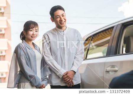 一位年輕的亞裔男性推銷員為一對前來採購、估價、購買汽車的夫婦服務。 131372409