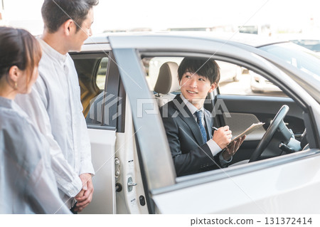 A young Asian male salesman serving a couple who came to buy, assess and purchase a car A young Asian male salesman serving a couple who came to buy, assess and purchase a car 131372414