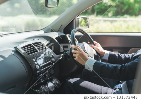 A young male businessman in a suit driving a car 131372443