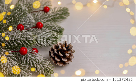 Winter holiday background: Snow-covered fir branches, pine cone and golden bokeh lights. 131372455