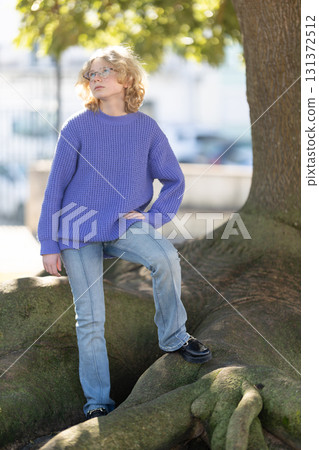 Young girl standing on tree root thinking outdoors Young girl standing on tree root thinking outdoors 131372512