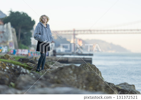 Young woman standing by river looking thoughtful 131372521