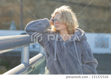 Thoughtful young person leaning on railing contemplating Thoughtful young person leaning on railing contemplating 131372526