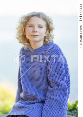 Young person with curly hair wearing purple sweater Young person with curly hair wearing purple sweater 131372533