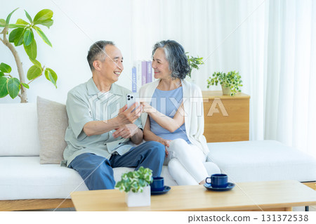 一對老夫婦在客廳裡看智能手機 一對老夫婦在客廳裡看智能手機 131372538