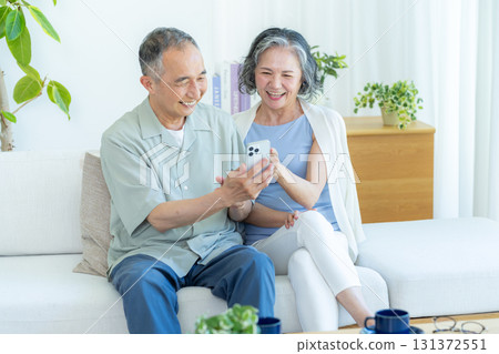 Senior couple looking at a smartphone in the living room Senior couple looking at a smartphone in the living room 131372551