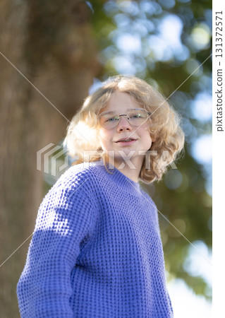 Young blonde person wearing glasses and purple sweater 131372571