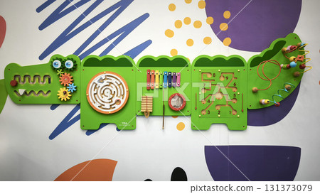Interactive wall-mounted sensory play panel for kids, shaped like a crocodile, featuring gears, mazes, musical instruments, and bead games for hands-on learning and fun. Interactive wall-mounted sensory play panel for kids, shaped like a crocodile, featuring gears, mazes, musical instruments, and bead games for hands-on learning and fun. 131373079