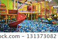 Colorful indoor playground with slides, climbing structures, and a ball pit full of blue, white, and black plastic balls, perfect for kids fun and birthday parties.  131373082