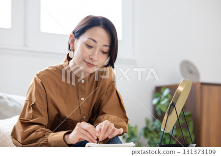 一位女士在客廳對著鏡子戴耳環 131373109
