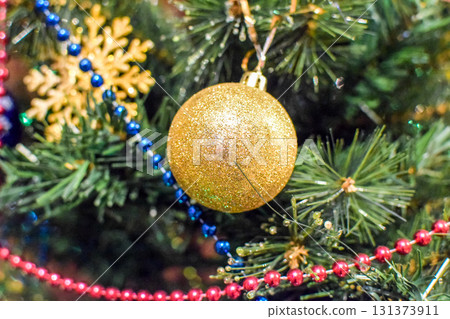 Decorations New Year tree. Tinsel and toys, balls and other decorations on the Christmas Christmas tree standing in the open air. Decorations New Year tree. Tinsel and toys, balls and other decorations on the Christmas Christmas tree standing in the open air. 131373911