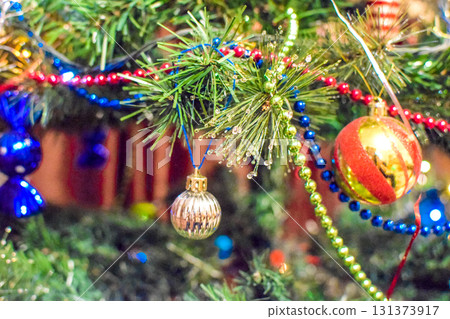 Decorations New Year tree. Tinsel and toys, balls and other decorations on the Christmas Christmas tree standing in the open air. Decorations New Year tree. Tinsel and toys, balls and other decorations on the Christmas Christmas tree standing in the open air. 131373917