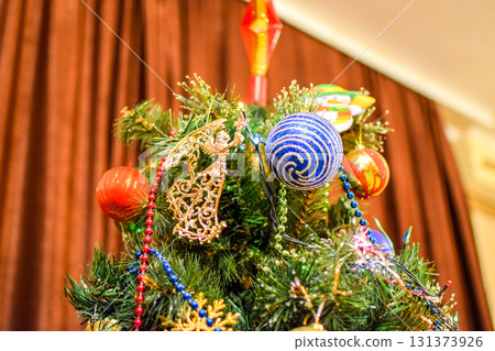 Decorations New Year tree. Tinsel and toys, balls and other decorations on the Christmas Christmas tree standing in the open air. 131373926