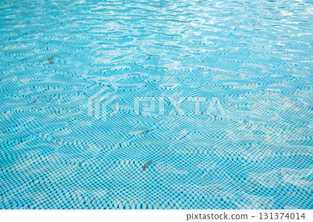 Pool water reflecting sunlight and ripples, creating a tranquil blue environment for relaxation and leisure 131374014