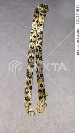 A gold necklace with a leopard print. Handcrafted with small beads 131374653