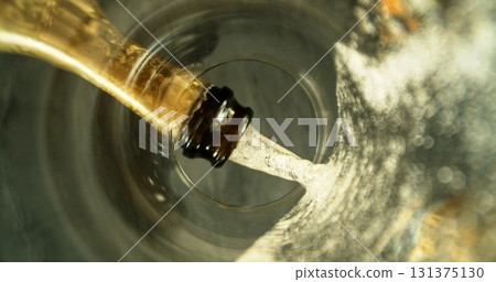 Champagne Wine Pouring into Glass. Unique Perspective View from the Bottom on the Glass. 131375130