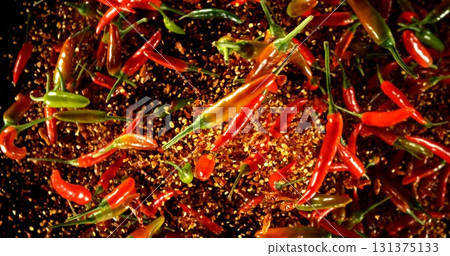 Falling chili peppers on a black background. Spices in motion. Falling chili peppers on a black background. Spices in motion. 131375133