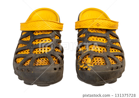 dirty worn yellow and black garden rubber sandals or shoes with perforated design isolated on white background. Front view dirty worn yellow and black garden rubber sandals or shoes with perforated design isolated on white background. Front view 131375728